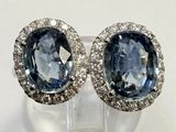 une paire de boucles d'oreilles en saphir bleu et diamants posées sur une surface transparente