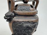 a bronze urn with a dragon handle on a stand