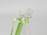 a glass bottle with a green ribbon and a butterfly on it