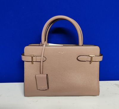 un sac à main beige posé sur une table devant un mur bleu