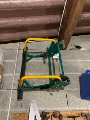 un chariot vert avec des outils posés par terre, à côté d'un tas de bois