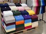 de nombreux t-shirts de différentes couleurs posés sur une palette dans un magasin