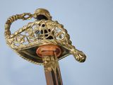 a close up of a gold sword with a blue stone on it