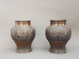 deux vases en argent posés l'un à côté de l'autre sur une table