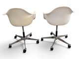 two white chairs on casteors with wheels on a white surface