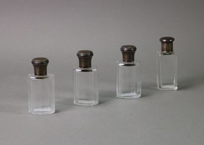 three small glass bottles with silver lids on a table