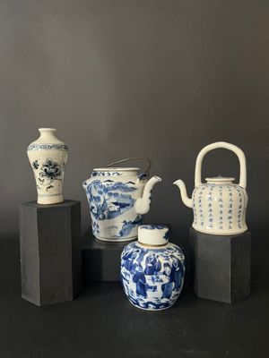 four blue and white vases and a teapot on a black table
