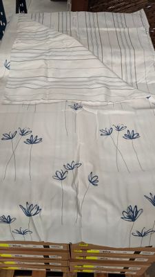 un couvre-lit orné de fleurs bleues, posé sur des palettes dans une pièce