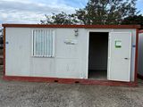 a small white and red building with a door open