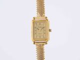 a close up of a gold wrist watch with a chain around it
