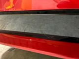 the rear end of a red car with a black stripe