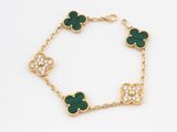 a close up of a gold bracelet with green and white stones