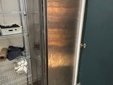 a silver refrigerator in the corner of a room next to a green door