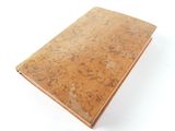 an old book sitting on top of a table on a white surface