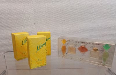 trois boîtes de parfum posées sur une table en verre