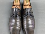 pair of men ' s leather shoes with laces on a gray surface
