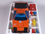 un petit camion orange avec un toit bleu et un camion rouge et blanc