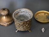 a silver cup sitting next to a gold candle holder