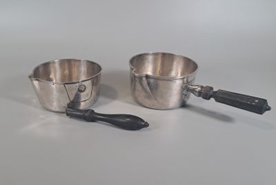deux casseroles en argent et une cuillère posées sur une table