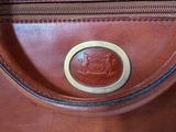 a close up of a brown leather bag with a metal handle