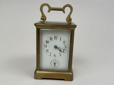 a small brass clock with a white face on a white surface