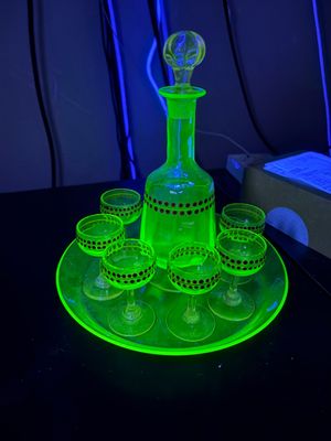 une carafe à liqueur en verre vert fluo, accompagnée de six verres et d'une autre carafe, le tout présenté sur un plateau