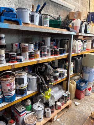 de nombreux pots de peinture posés sur une étagère dans un garage