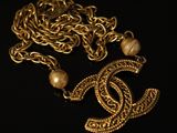 un gros plan d'un collier en or orné de perles sur fond noir