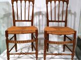 une paire de chaises anciennes en bois avec des assises en osier, exposées