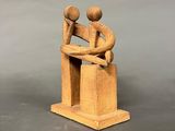 wooden figurine of a man and a woman sitting on a bench