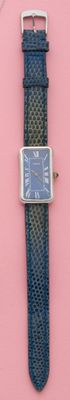 une montre posée sur un support rose, avec un bracelet bleu
