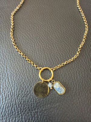 a gold necklace with a coin and two charms on it