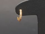 a close up of a pair of gold hoop earrings on a black stand