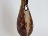 a brown and white vase on a stand on a white surface