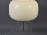 a white table lamp with a metal tripod base and a white glass shade