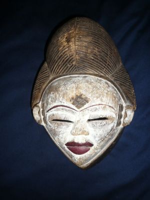 un vieux masque en bois posé sur un tissu bleu à fond noir