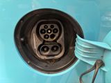 a close up of a blue car with an electric plug in it