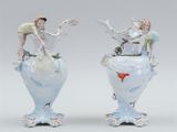 pair of porcelain vases with figures on top of them