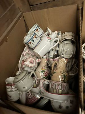 a cardboard box filled with many different types of cups and mugs