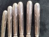 five silver spoons are lined up in a row on a black surface