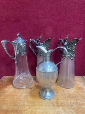 trois vases en argent posés sur une table, sur fond rouge