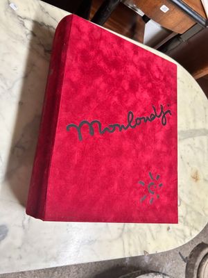 someone is writing on a red book on a marble table