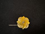 un gros plan d'une broche en forme de fleur dorée sur fond noir