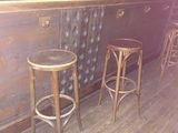 two wooden stools sitting in front of a bar