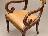 une chaise en bois avec une assise et des accoudoirs en cuir beige