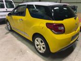 the rear end of a small yellow car parked in a garage
