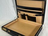 a black suitcase with a gold handle on a white table