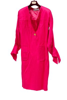 une robe rose suspendue à un cintre, sur fond blanc