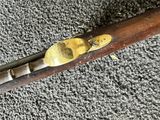 an old wooden rifle with a brass plated handle on a carpet