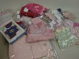 une pile de vêtements pour bébés et d'autres objets posés sur une table